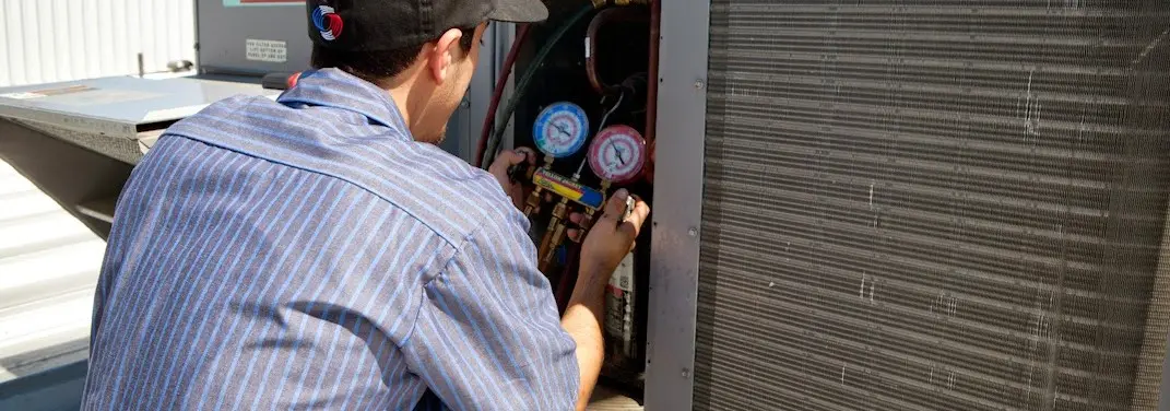 HVAC technician servicing a condenser unit in Milan
